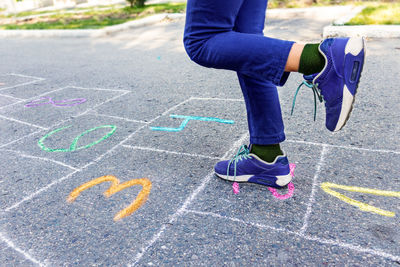 Girl in jeans playing hopscotch painted on asphalt,happy childhood, summer games  playground