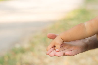 Close-up of baby holding fingers outdoors