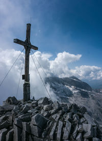 Low angle view of cross on rock against sky