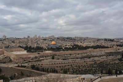 Aerial view of cityscape against cloudy sky