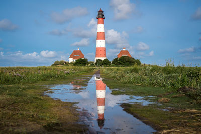 Lighthouse by building against sky