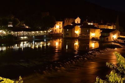 Illuminated buildings by river at night