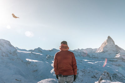 Man standing on snowcapped mountain against sky