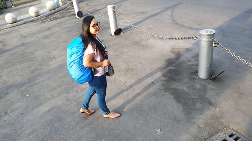 High angle view of young woman standing with backpack on road