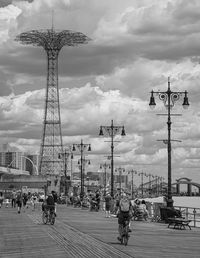 People at amusement park against cloudy sky