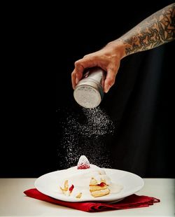 Midsection of man holding ice cream on table against black background