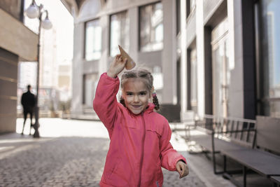 Portrait of woman with arms raised in city