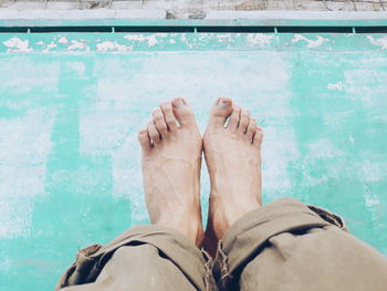 Low section of man standing by swimming pool