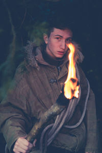 Boy holding flaming torch in cave