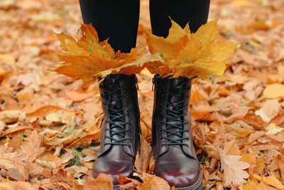 Low section of person standing on autumn leaves