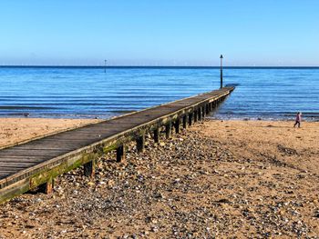 Wooden posts on beach against clear sky