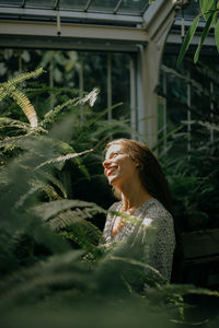 Front view of a young woman amidst plants during sunset