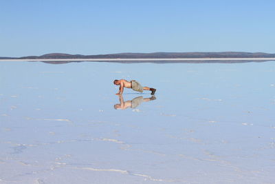 Man surfing in water against clear sky