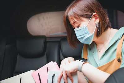 Close-up of woman wearing mask sitting with shopping bags in car