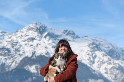 Mid adult woman standing on snow covered mountain against sky