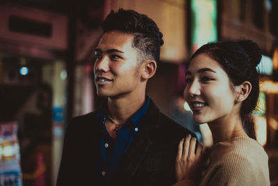 Smiling couple standing on street in city at night