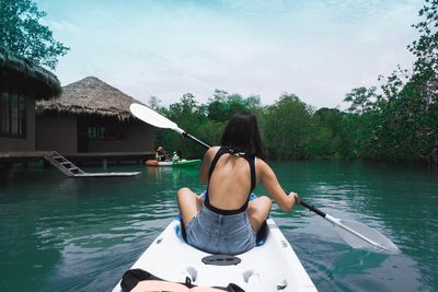 Rear view of woman sitting in rowboat against sky