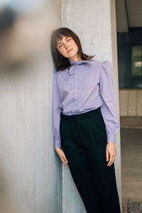 Portrait of woman standing against wall