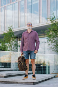 Portrait of young man standing against building