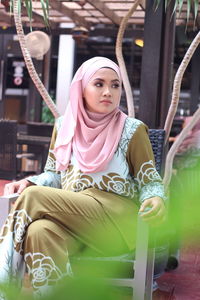 Young woman looking away while sitting on chair