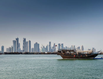 Sea and buildings in city against clear sky