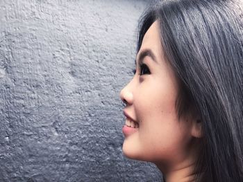 Close-up of smiling woman looking away against wall