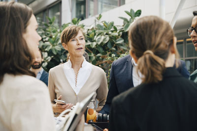 Mature female entrepreneur talking to coworkers in office seminar