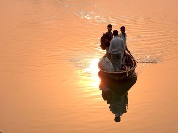 Rear view of man in boat on lake during sunset