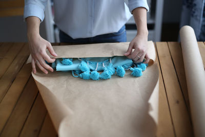 Woman packs a handicraft thing into craft paper, a small business and customer care.