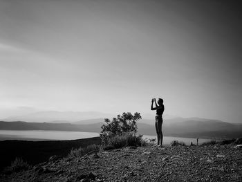Rear view of man standing on field against sky