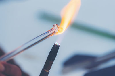Close-up of lit candle against sky