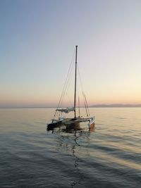 Sailboat in sea against clear sky during sunset