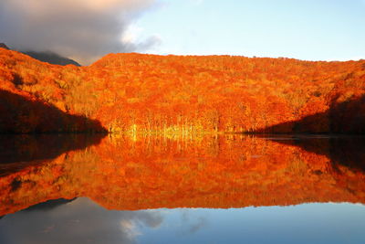 Scenic view of lake by mountain against sky during autumn