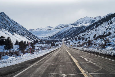 Road amidst snowcapped mountains against sky