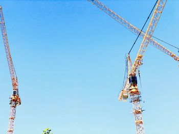 Low angle view of crane against clear blue sky