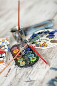 High angle view of messy palette with paintbrushes on table