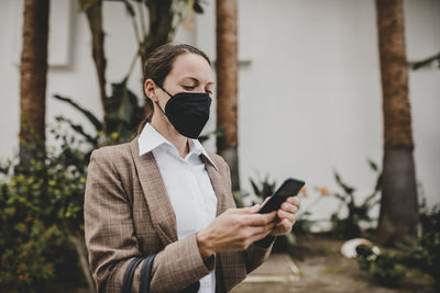 Man holding mobile phone standing outdoors