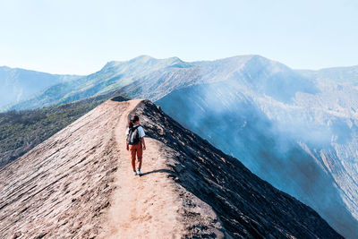 Rear view of man on mountain against sky