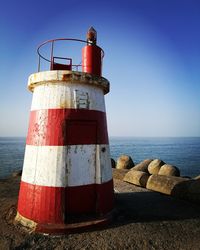 Lighthouse by sea against clear sky