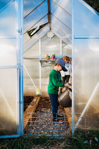 Young boy and girl using watering can in backyard during spring time