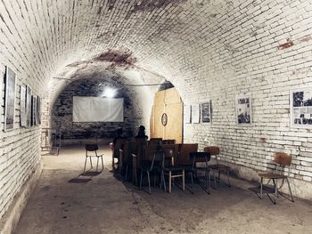 Empty chairs and table against wall in old building