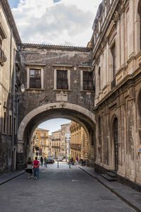 Beautiful street with historic buildings and a stone arch in catania