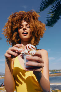 Portrait of young woman standing against sea against sky