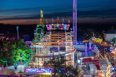 Illuminated amusement park against sky at night