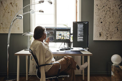 Businesswoman with disability having coffee while doing video call on computer at home office