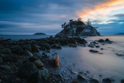 Rocks on beach against sky during sunset