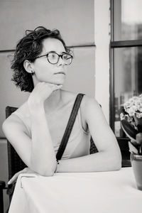 Portrait of young woman looking away while sitting on table