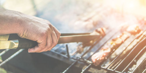 Cropped image of hand preparing barbecue