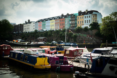 Boats moored at harbor against buildings in city