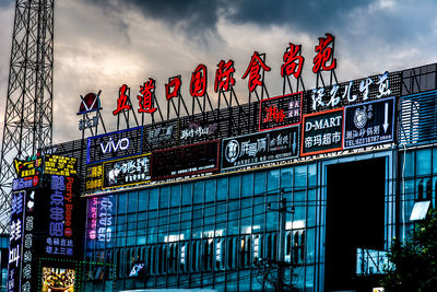 Low angle view of illuminated text on building against sky